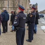 Two Brantford police officers stand in a crowd.